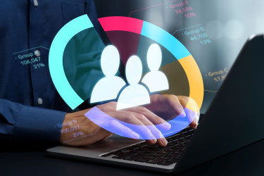 Person typing on a laptop with a colorful chart and user icons overlaid, representing customer data or audience analytics.