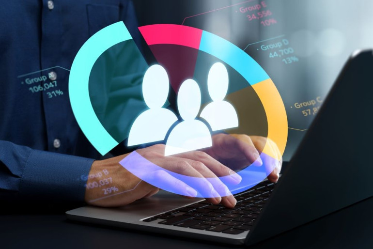 Person typing on a laptop with a colorful chart and user icons overlaid, representing customer data or audience analytics.